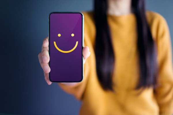 Person holding a phone with a smiley face.